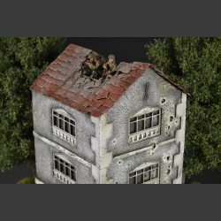 Two-story building with bullet holes and bombed roof